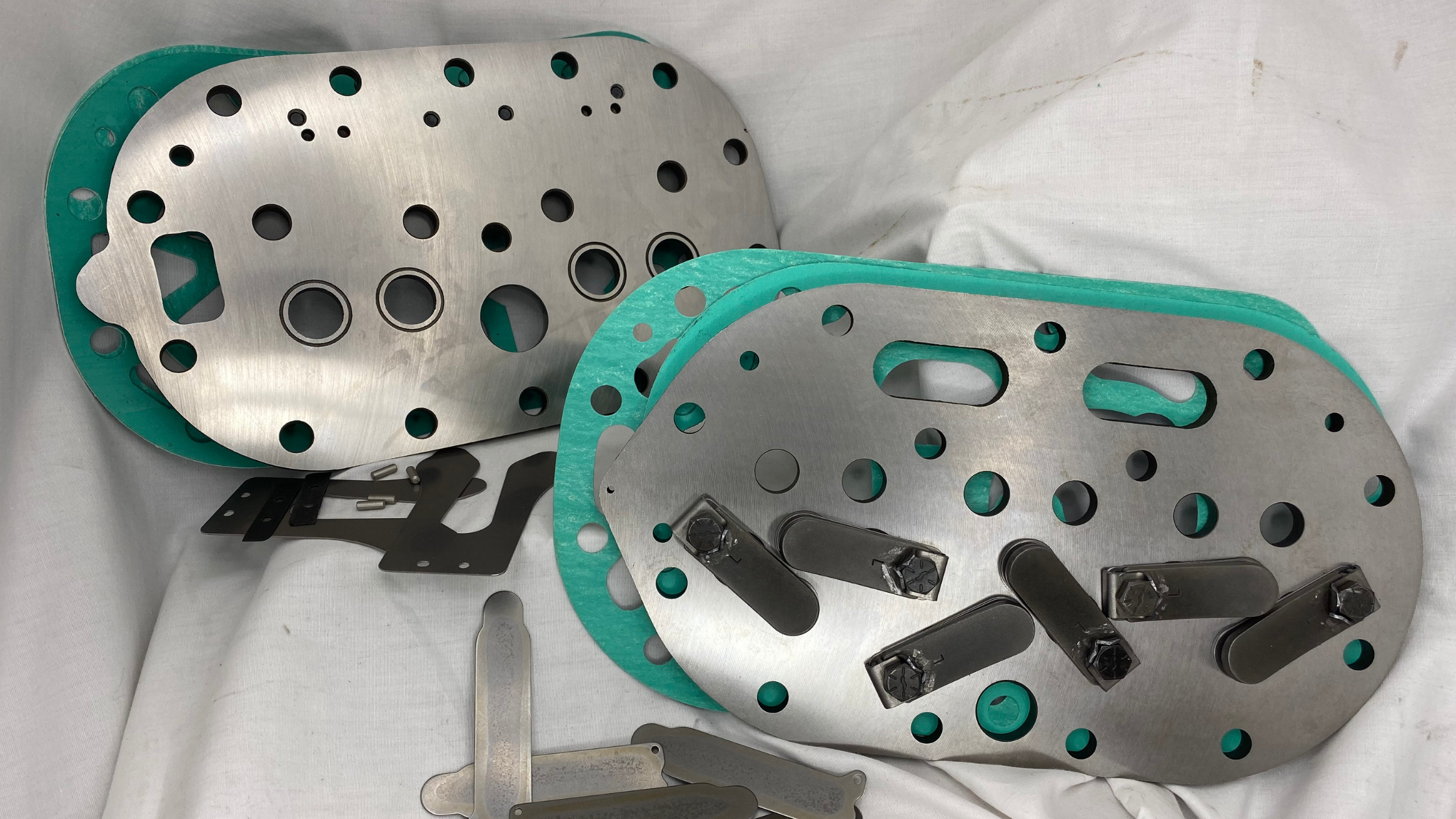 Copeland compressor valve plates with green gaskets and metal components, essential for maintaining compressor efficiency and reliability.